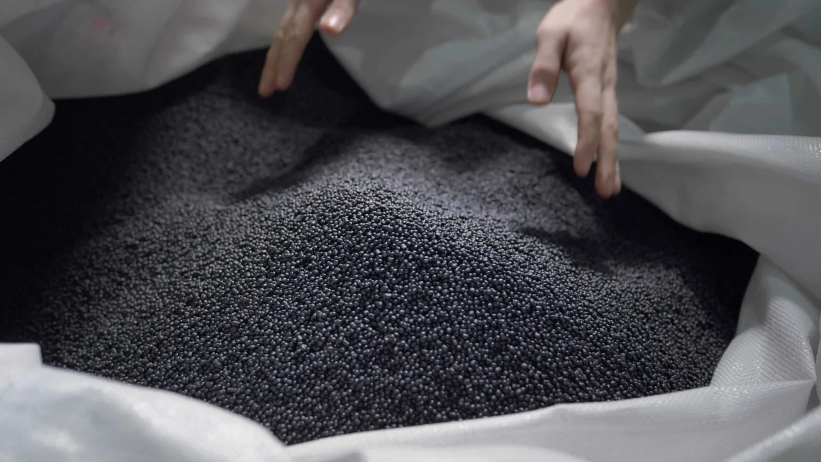 Close-up of black granular material in a white bag, possibly for industrial use.